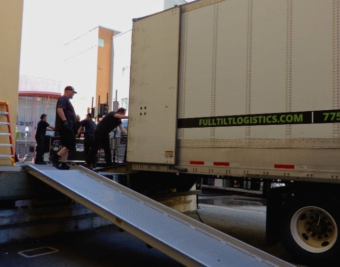 A team is unloading audio visual equipment into a venue off of a Full Tilt Touring truck